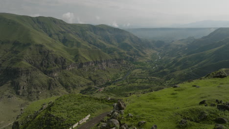turista masculino en una montaña admirando la vista del paisaje natural verde y el río en georgia