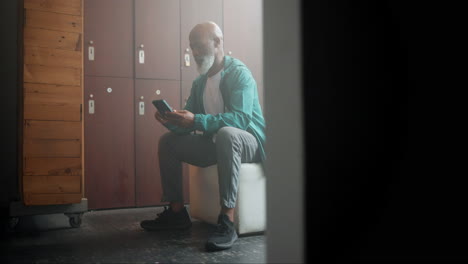 senior man using cell phone in locker room