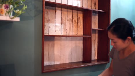 asian woman painting wooden shelves at home