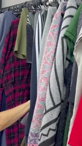 rows of secondhand clothes hang on hangers a woman buys used clothes rows of secondhand clothes hang on hangers a woman buys used clothes