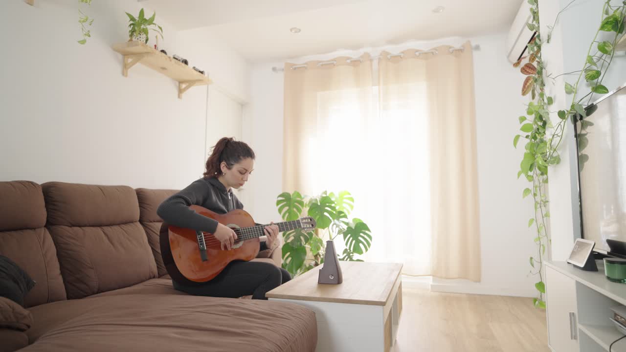 Young woman playing acoustic guitar in cozy living room