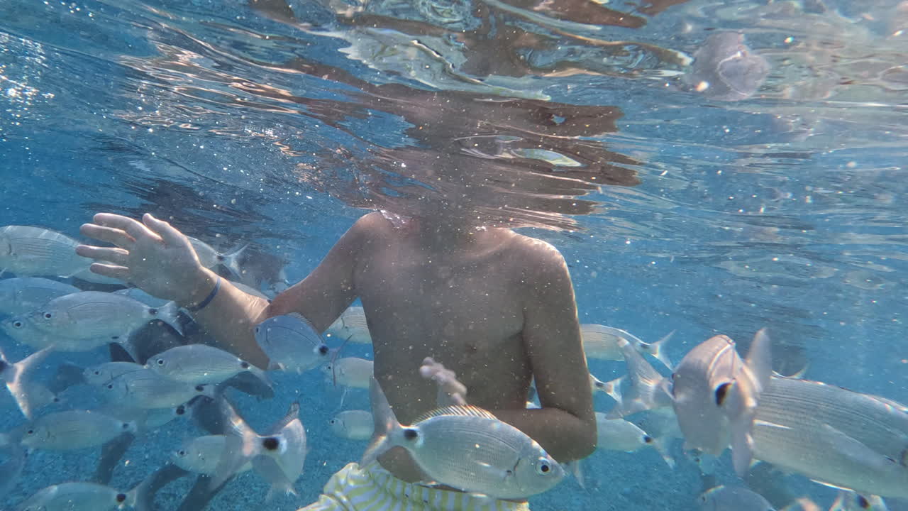 물속의 십대가 물고기로 둘러싸여 있습니다.
