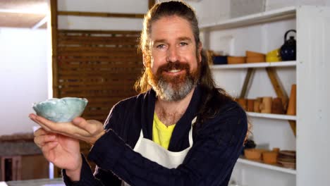 happy male potter holding bowl