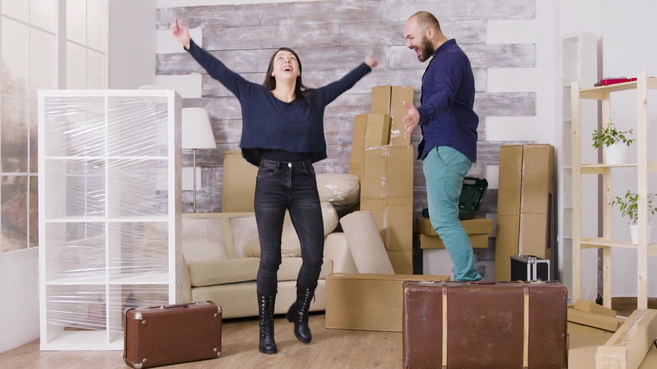 Happy Couple Jumping and Celebrating in Their New Apartment