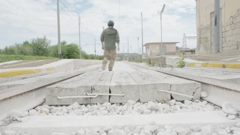 man crossing old railroad, walking far and returning near