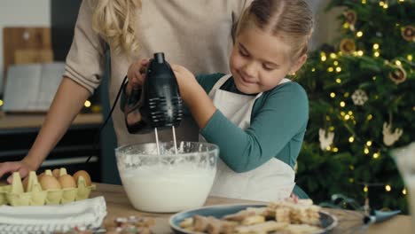 Caucasian-mother-and-daughter-preparing-baking-using-electric-mixer-in-the-kitchen-before-Christmas.