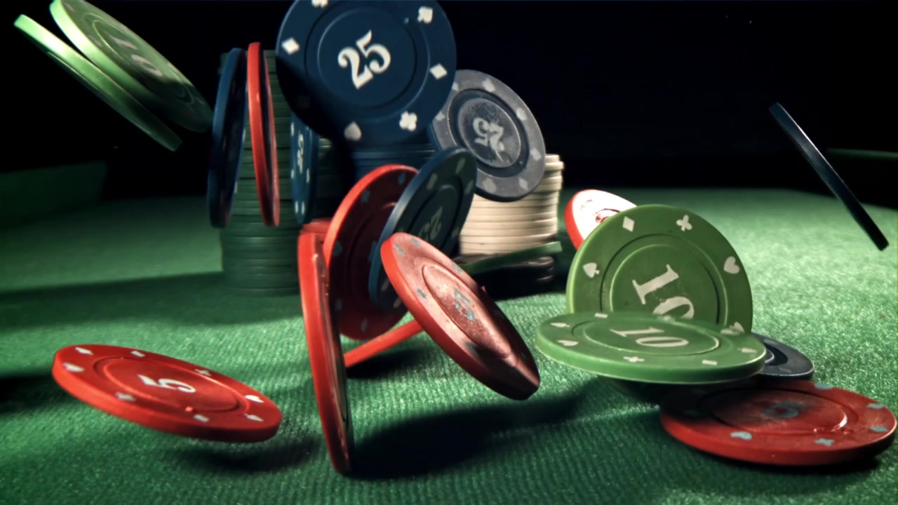 Fiches da poker che cadono e si disperdono su un tavolo di feltro verde.