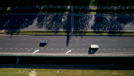 Top-down-ascending-view-above-highway-merge-left-lane,-half-covered-in-shadows-from-trees