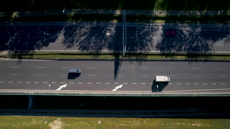 top down ascending view above highway merge left lane, half covered in shadows from trees