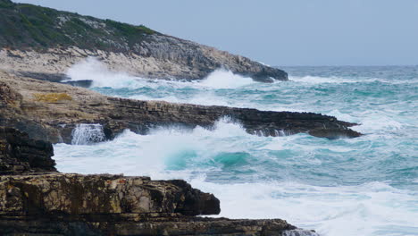 Olas-Del-Mar-Rompiendo-En-La-Costa-Rocosa-Creando-Espuma-Y-Niebla-En-Clima-Tormentoso