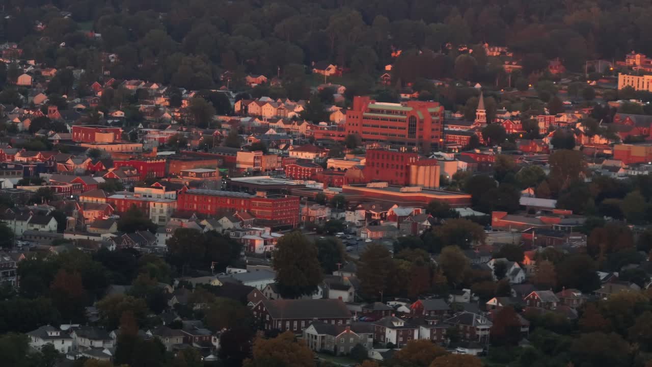 Beuautifuk historic downtown buildings lighting on golden sunlight. Suburb housing area in shadow at dusk. Aerial wide shot. Red brick buildings in downtown of ephrata, Virginia. Summer season in USA