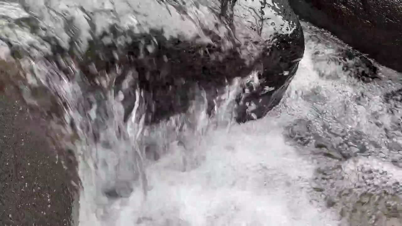 Acqua limpida che scorre sopra rocce scure del fiume