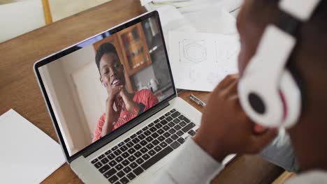 Afroamerikanischer-Männlicher-College-Student,-Der-Notizen-Hält,-Während-Er-Zu-Hause-Einen-Videoanruf-Auf-Dem-Laptop-Führt