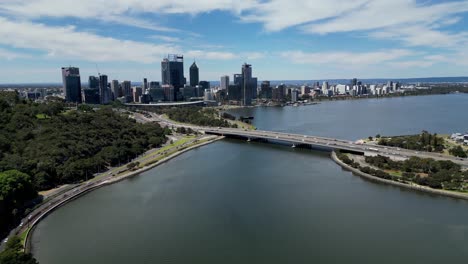 Vista-Aérea-Panorámica-De-La-Autopista-Del-Puente-Narrows-En-El-Río-Swan-Con-La-Vista-De-Los-Edificios-Del-Horizonte-Del-Sur-De-Perth-En-El-Fondo,-Perth,-Australia-Occidental