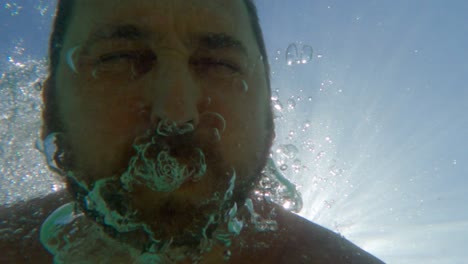 unusual underwater view of man breathing out air to create bubbles