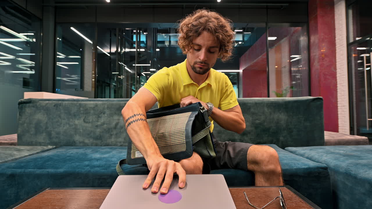Man in yellow shirt packing up his things and going home from work