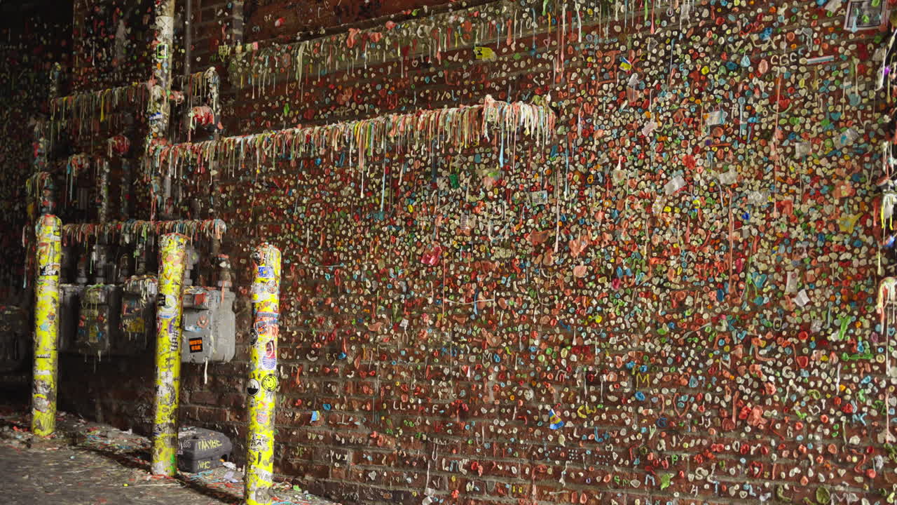 Fixed shot of the iconic gum wall showing thousands of colorful pieces stuck to brick
