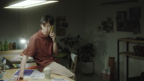 a young man making a phone call in a dimly lit design studio