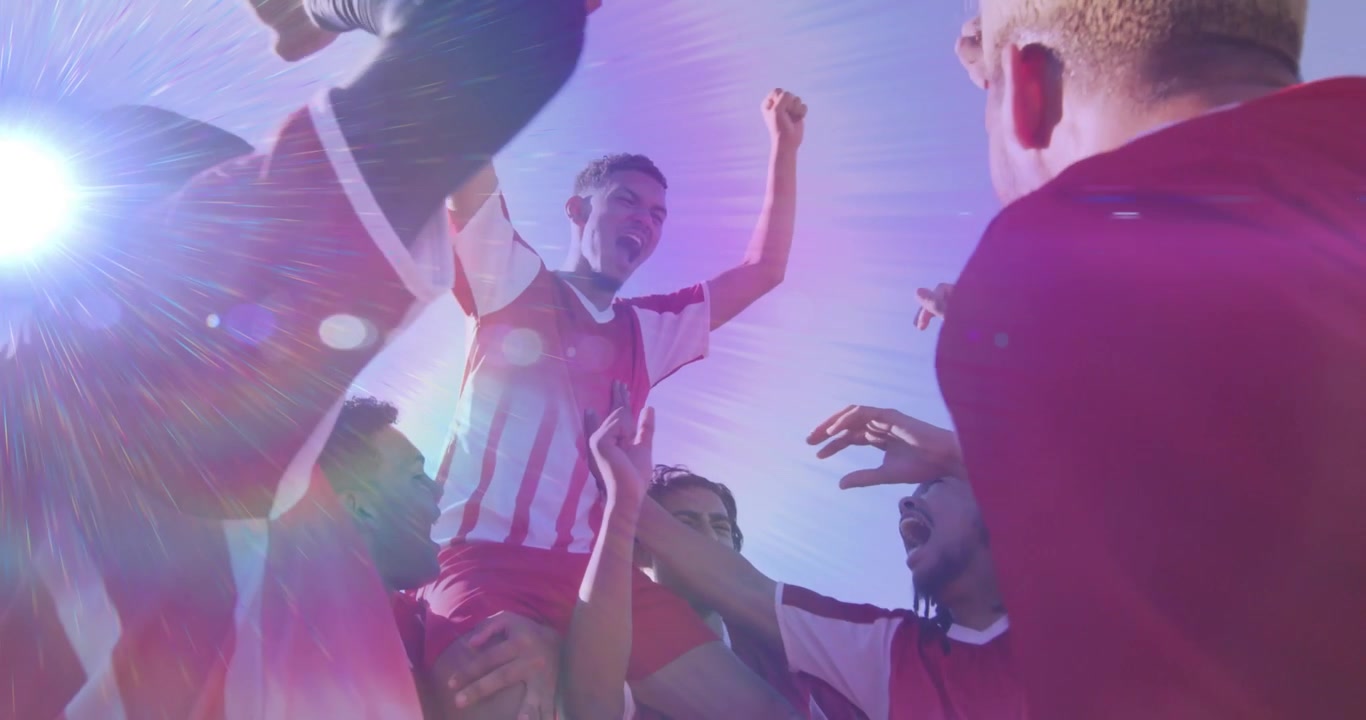 Equipo de fútbol celebrando la victoria levantando a un compañero en un campo soleado, mostrando confeti animado.