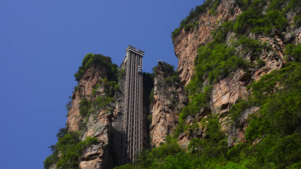 Low angle view of Bailong Elevator in operation, built into the side of cliff with clear blue sky, China
