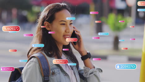 animación de iconos de las redes sociales contra una mujer asiática feliz hablando con un teléfono inteligente en la calle