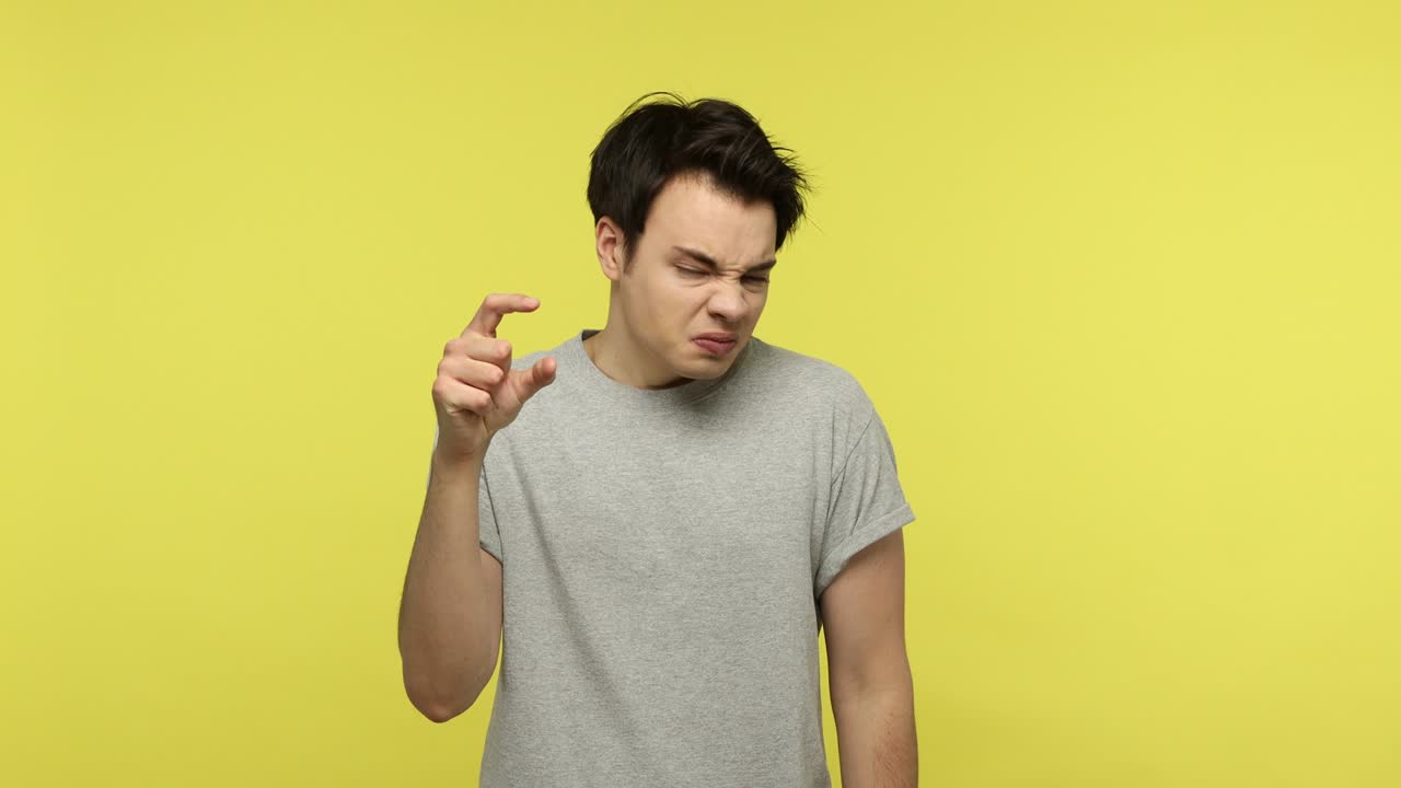 작은 크기, 낮은 비율에 불만족한 젊은이가 약간의 제스처를 보여줍니다.