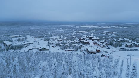 flying down into the winter spruce forest, in the background a panorama of the city of levi