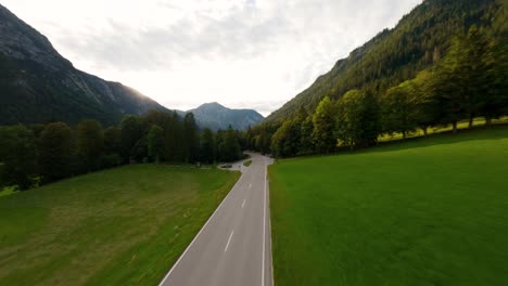 Drone-FPV-flying-above-an-empty-alpine-road-in-the-mountains-surrounded-by-a-forest-pine-trees-in-the-region-of-Tyrol,-Austrian-Alps