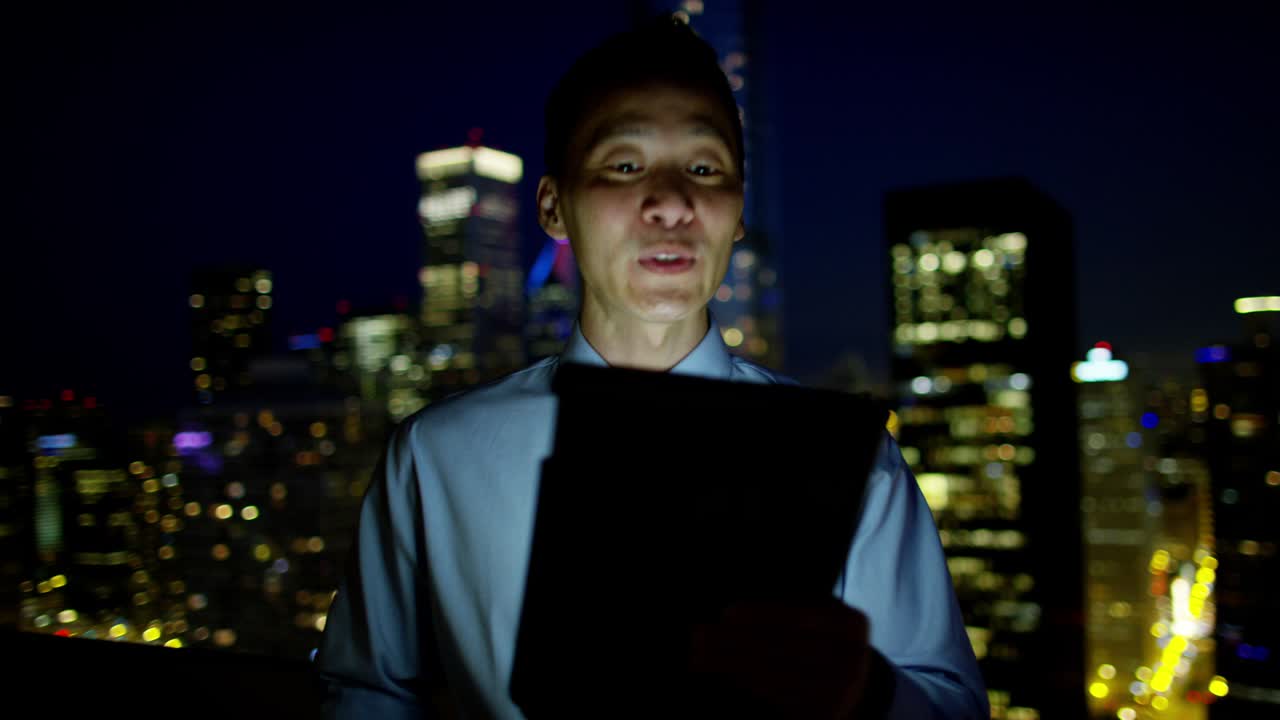Asian businessman video call on rooftop at night