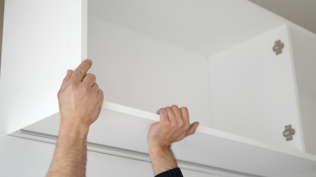 Uomo che assembla un mobile da cucina bianco