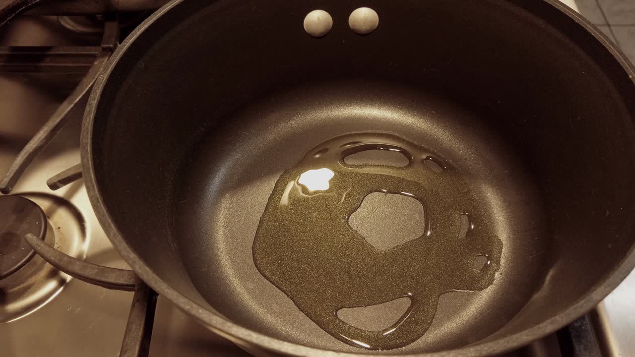 No person, non-stick pan on fire pouring olive oil, side profile shot.