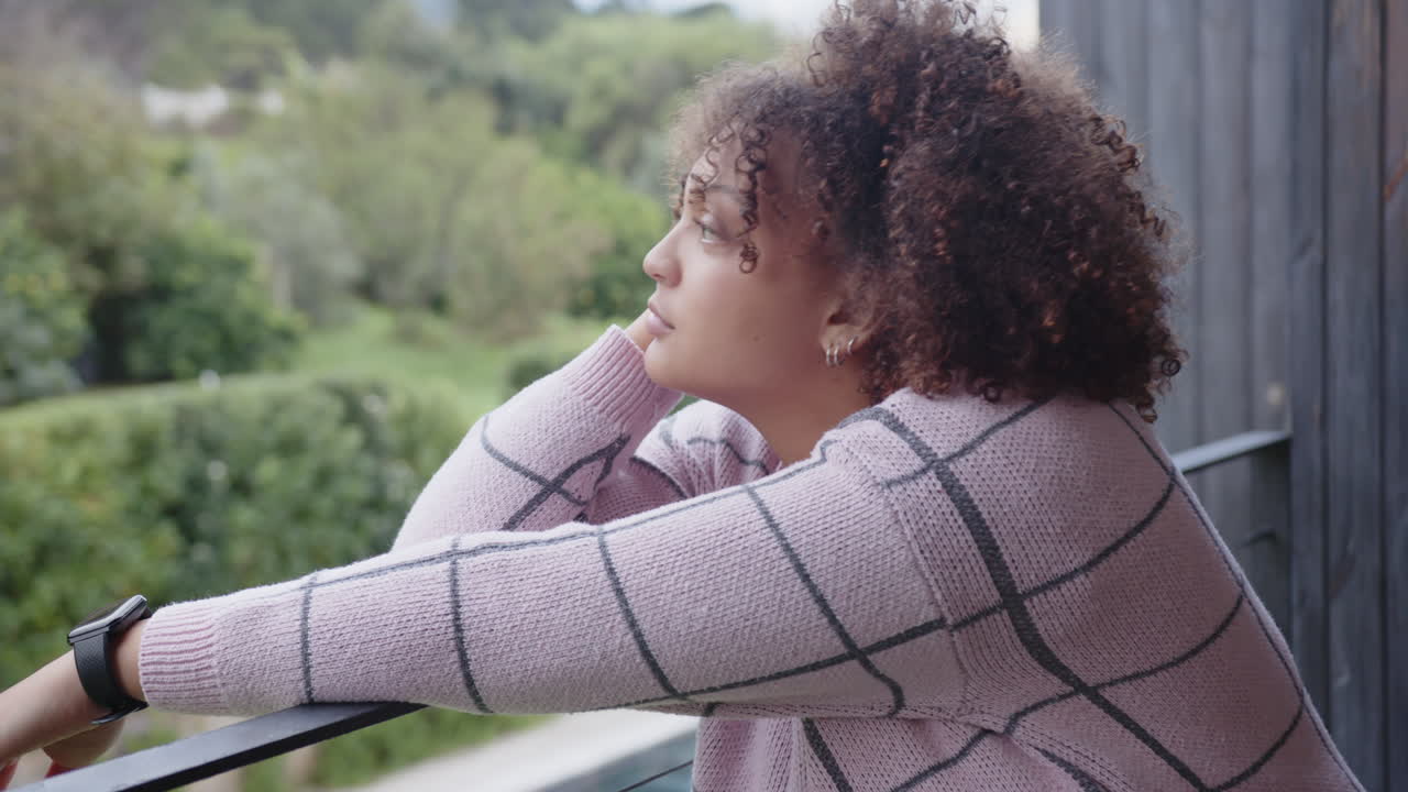Donna con maglione casual che si rilassa sul balcone, godendosi la vista sulla natura