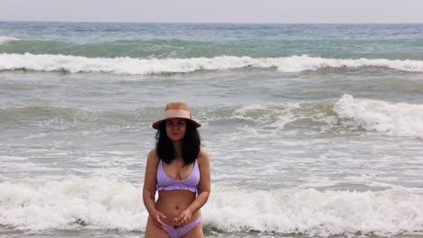 attractive girl wearing swimsuit and hat, walking on the beach - medium shot