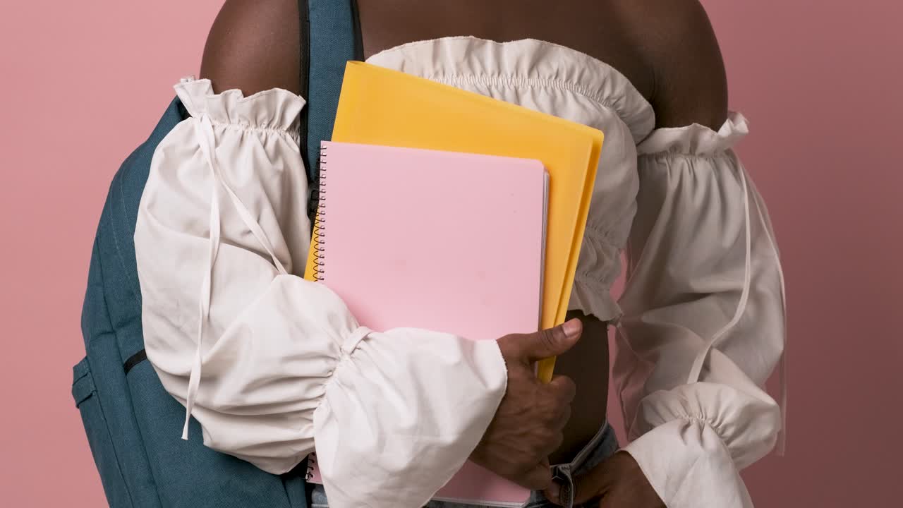 Crop black transgender student holding folder and notebook