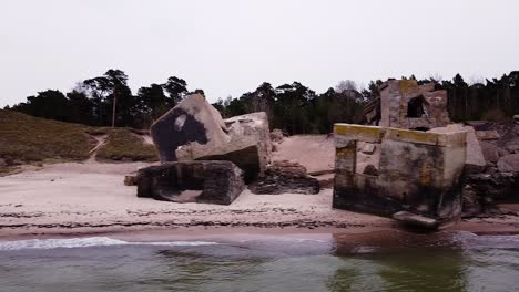 vista aérea del edificio abandonado de fortificación costera en los fuertes del norte de karosta en la playa del mar báltico en liepaja en un día nublado de primavera, amplio disparo de drones, plataforma baja