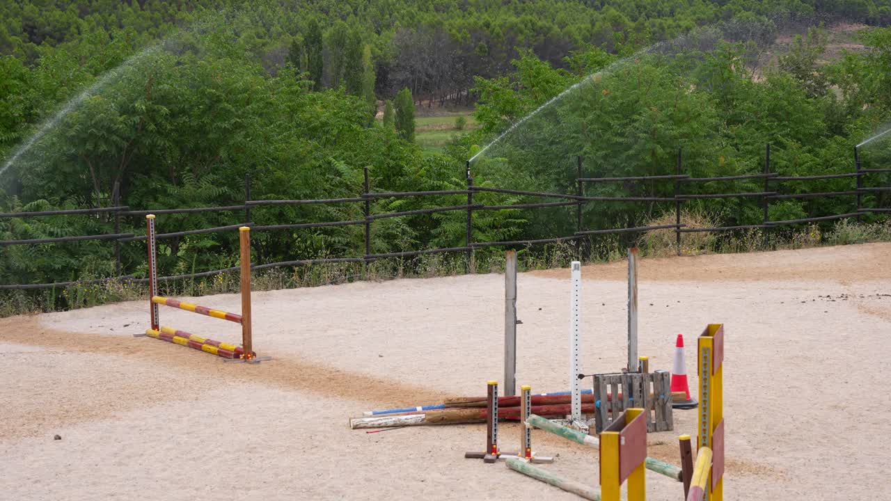 Bewässerungsanlagen bewässern die Reitbahn vor der Pferdetrainingseinheit