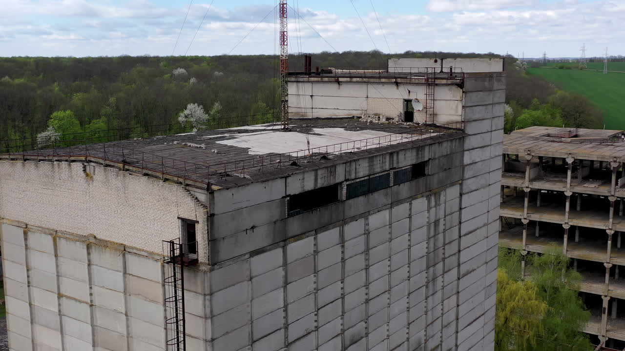 Ruined large building of a factory on green nature background. Old industrial plant with abandoned building. Abandoned factory.
