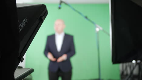 Fernsehmoderator-Spricht-Mit-Der-Kamera-über-Einen-Teleprompter-In-Einem-Green-Screen-Studio