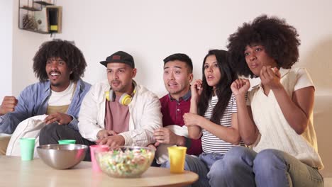 diverse group of friends reacting intensely while watching tv together