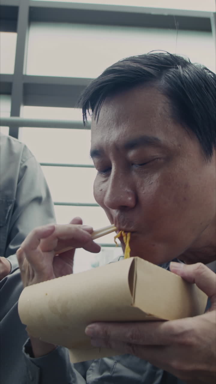 Asian Builder Eating Instant Noodles during Lunch Break