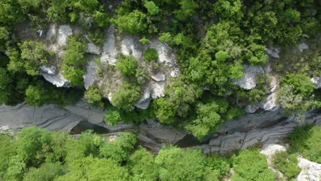 aerial top-down view of the papingo rock pools, also known as ovires, natural green water pools nestled in a small, smooth-walled gorge near the village of papingo in zagori region of epirus, greece