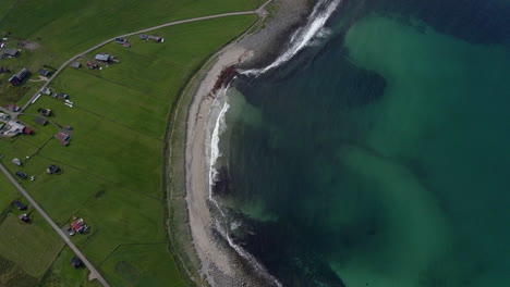 Aerial-shot-of-Unstad-beach-in-Lofoten,-tilting-up-and-revealing-beautiful-mountains