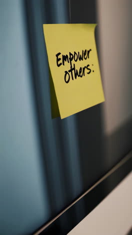 sticky note on a monitor saying "empower others"