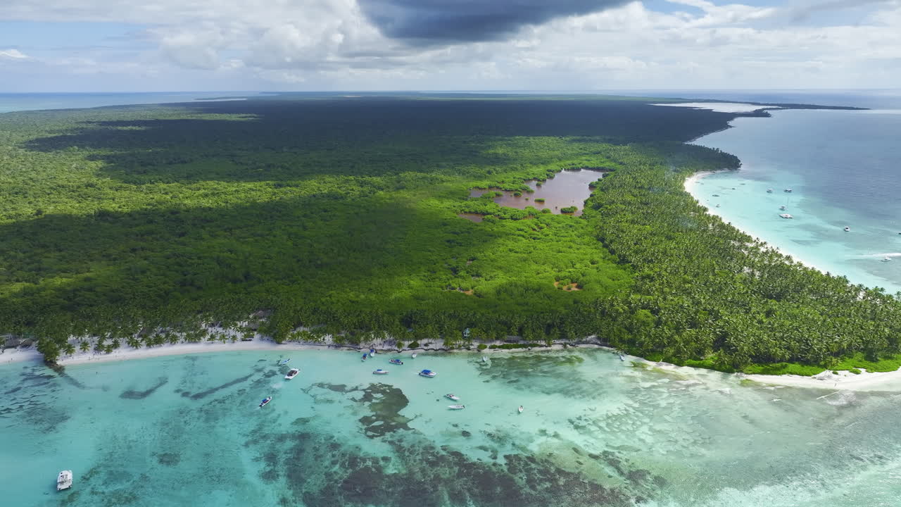 Panning from the left to the right side of the frame above a coastal area where resorts are located in the islands of the Dominican Republic in the Caribbean