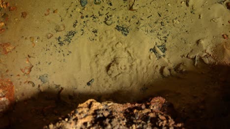 water flowing from underground in a cave moves the sand around it