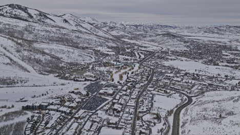 Park-City-Utah-Aerial-v76-high-altitude-drone-flyover-town-center-capturing-hillside-homes,-ski-slopes-and-mountain-landscape-covered-in-pristine-white-snows---Shot-with-Mavic-3-Cine---February-2023