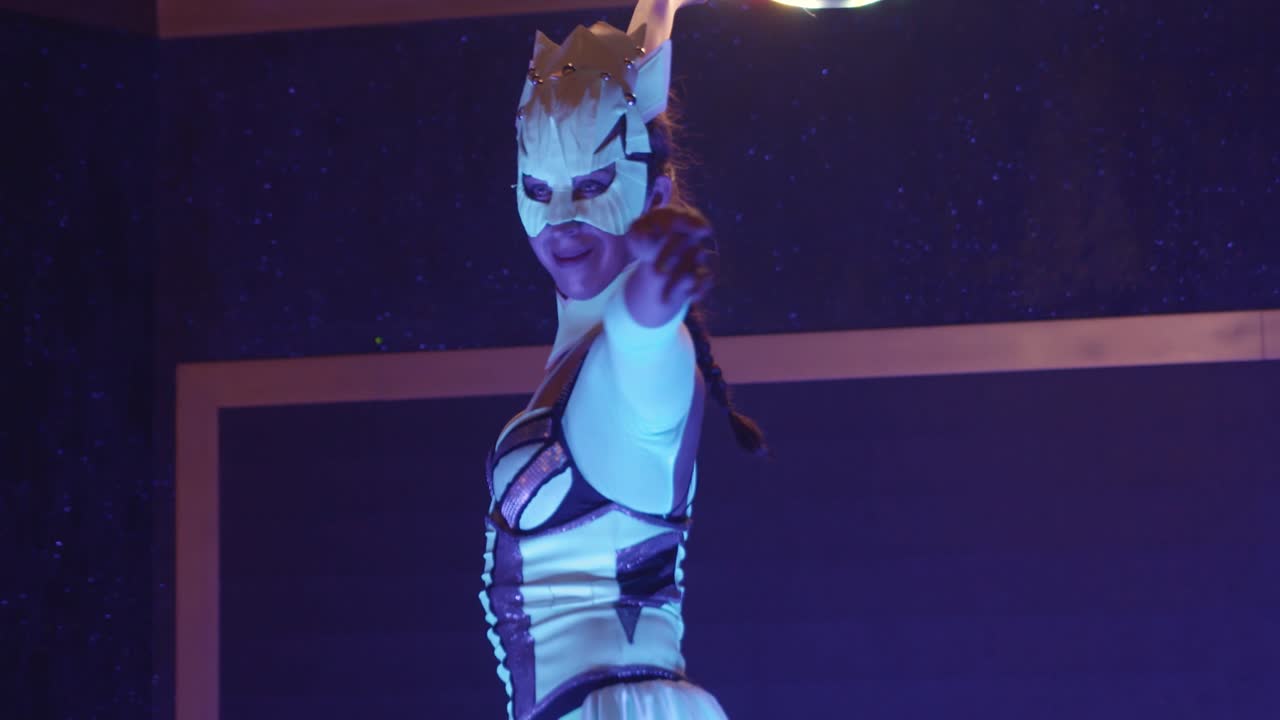 Tracking shot of woman in costume showing dance performance with lighting hula hoop.
