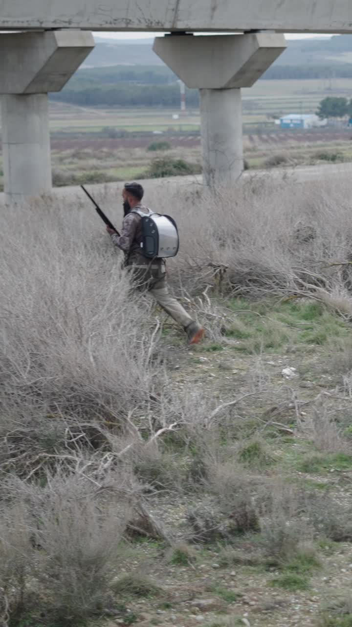 Man with rifle in camouflage clothing outdoors