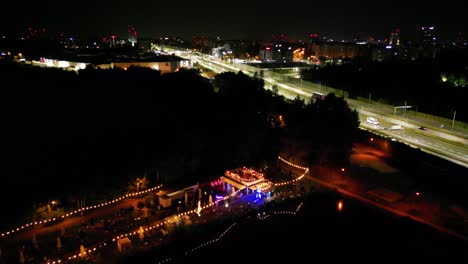 midnight traffic in katowice city, three pounds location - illuminated roads and lakeside bar - drone view 4k