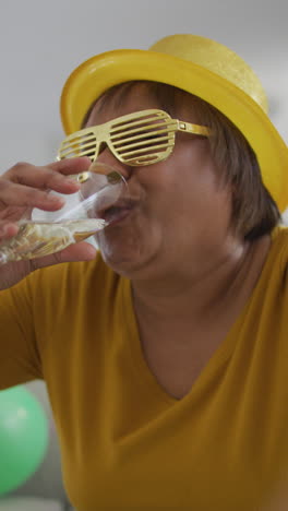 video de una anciana afroamericana con gafas de oro celebrando con champán
